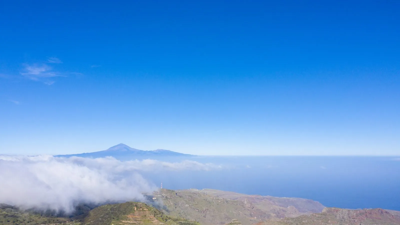 The green island of La Gomera in the foreground with Tenerife's Mount Teide rising beyond, a multi-island Canary vista