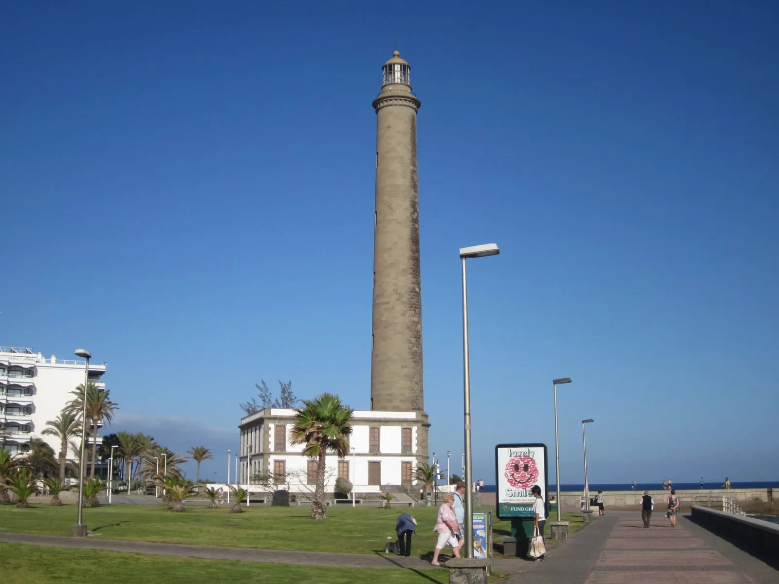 The tall Maspalomas lighthouse rising above the beach and promenade, Gran Canaria