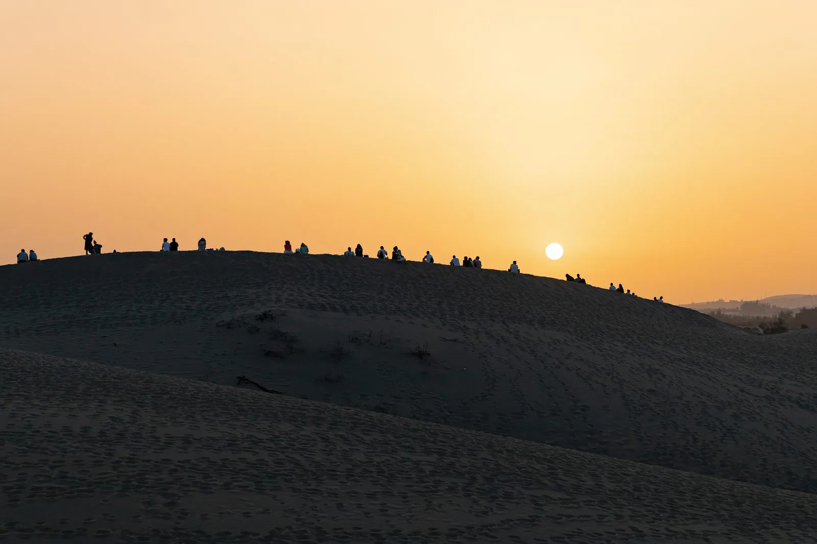 Visitors silhouetted on the ridges of the Maspalomas dunes at sunset, Gran Canaria